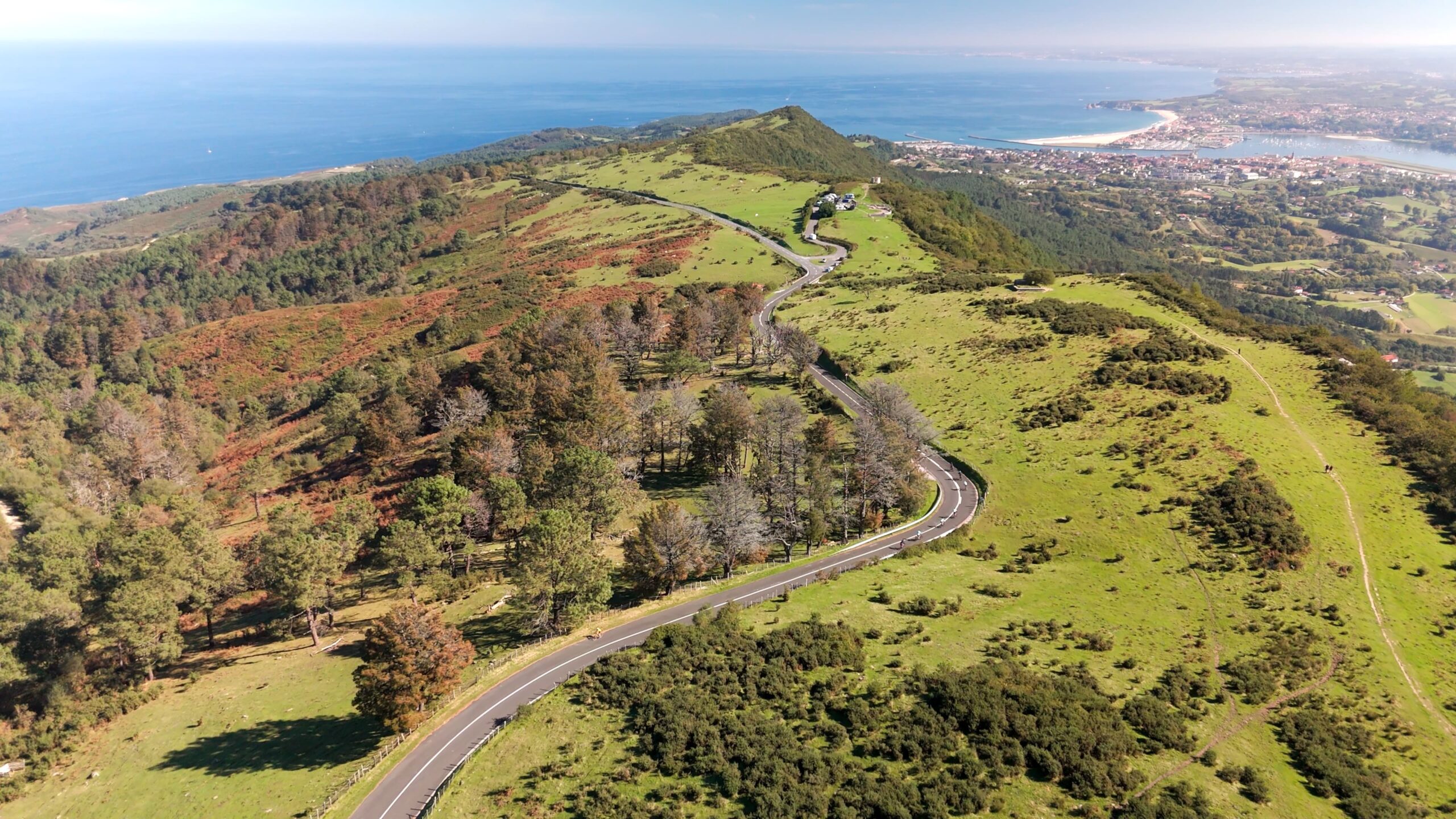 Aerial view of cyclists riding the scenic road above Hondarribia in the Basque Country overlooking the Bay of Biscay.